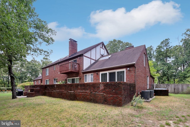 back of house with a balcony, a yard, and central AC