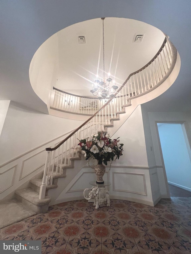 stairway with a high ceiling and an inviting chandelier