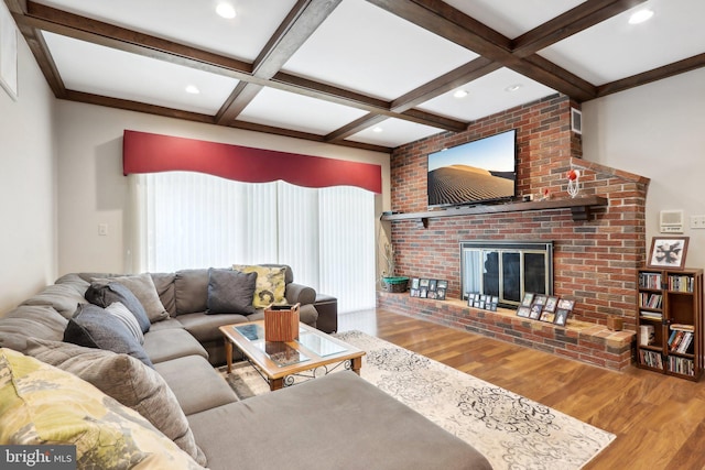 living room featuring beam ceiling, wood-type flooring, a fireplace, and coffered ceiling