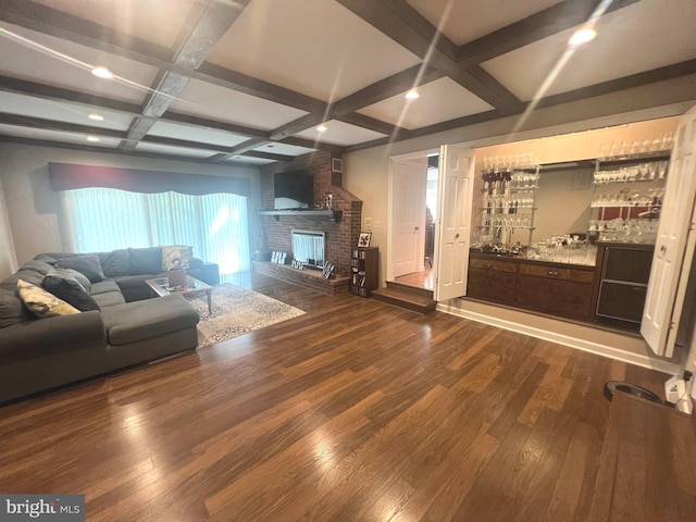 living room with coffered ceiling, a brick fireplace, dark hardwood / wood-style floors, indoor bar, and beamed ceiling