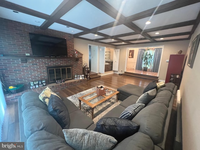 living room featuring a fireplace, wood-type flooring, beamed ceiling, coffered ceiling, and brick wall