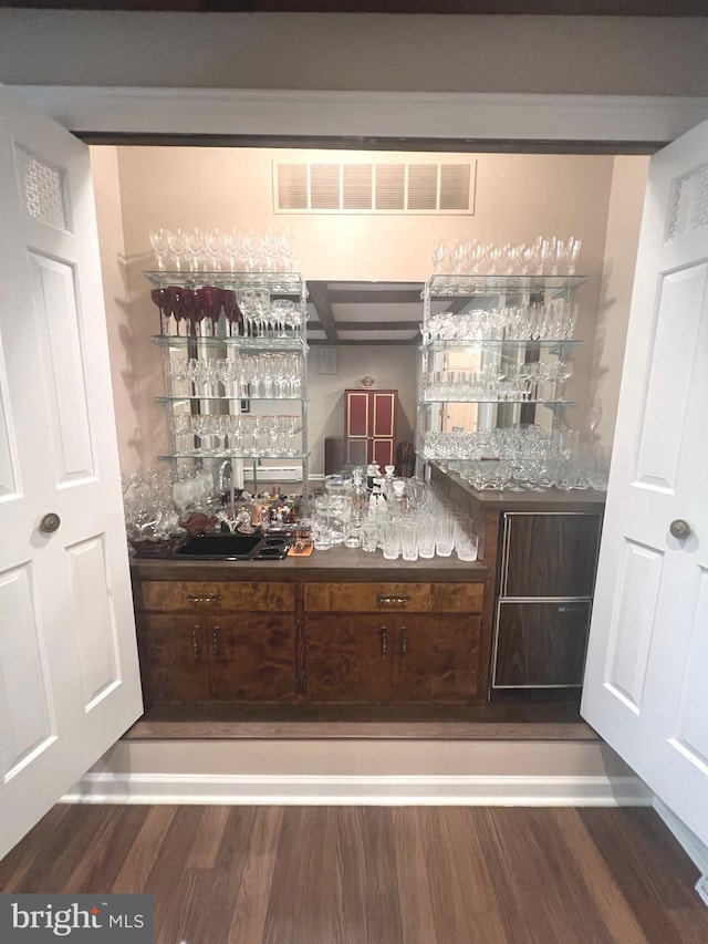 bar featuring dark wood-type flooring and dark brown cabinetry