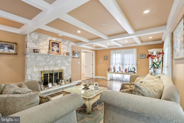 living room with beam ceiling, wood-type flooring, a stone fireplace, and coffered ceiling