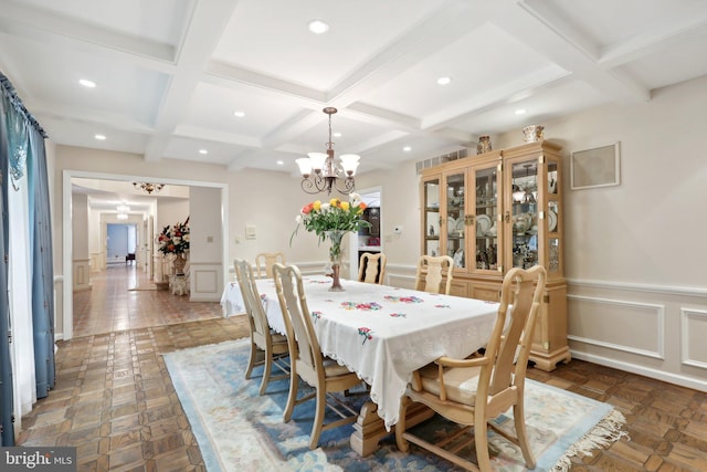 dining area with a chandelier, beamed ceiling, and dark parquet floors