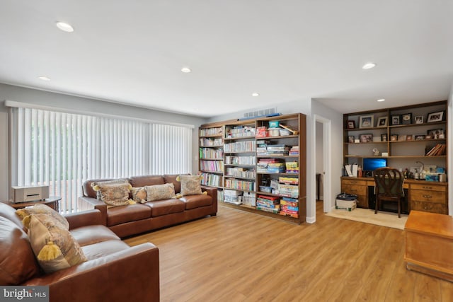 living room with built in features and light hardwood / wood-style floors