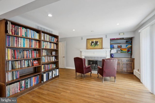 living area with baseboard heating and light hardwood / wood-style floors