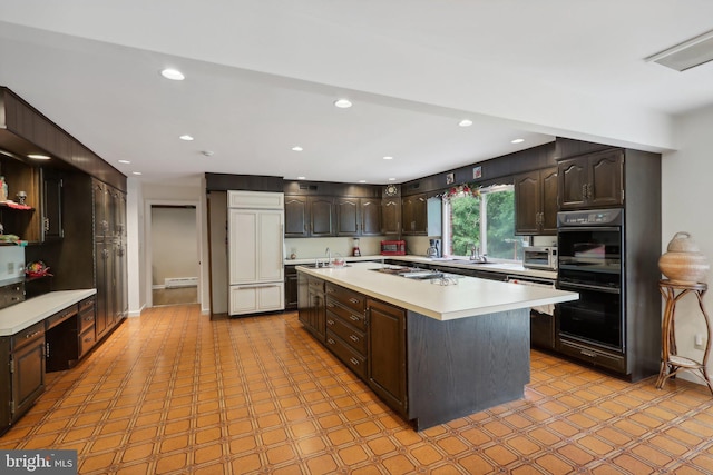 kitchen featuring sink, black double oven, dark brown cabinets, and a center island