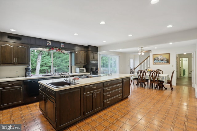 kitchen featuring dishwasher, ceiling fan, dark brown cabinets, and an island with sink