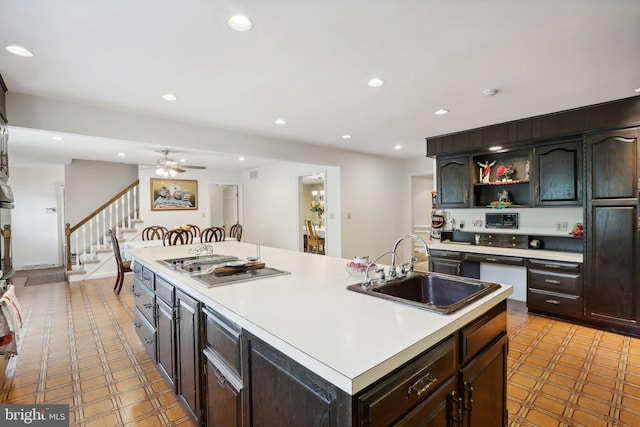 kitchen featuring a center island with sink, ceiling fan, stainless steel gas cooktop, dark brown cabinets, and sink