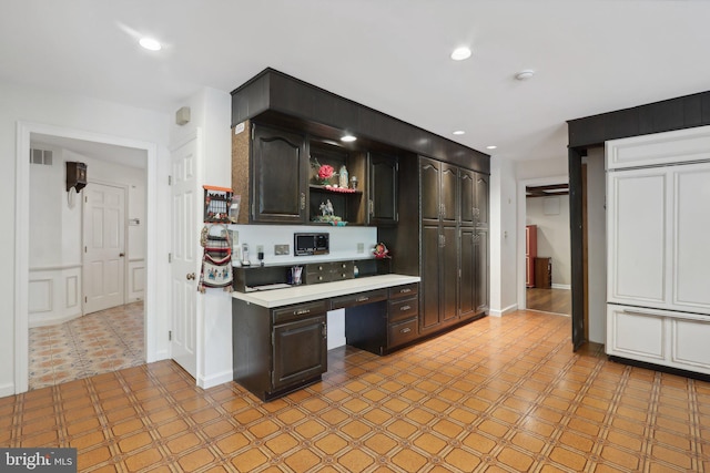 kitchen with ceiling fan, dark brown cabinetry, and built in desk