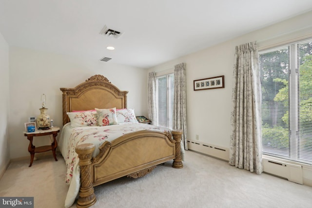 carpeted bedroom with a baseboard heating unit and multiple windows