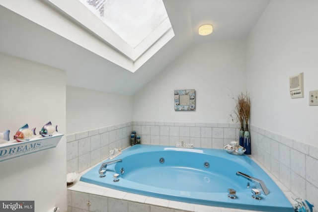 bathroom with tiled tub and lofted ceiling with skylight