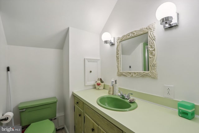 bathroom featuring toilet, vanity, and vaulted ceiling