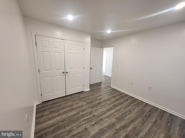 unfurnished bedroom with dark wood-type flooring and a closet