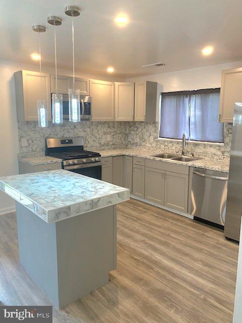 kitchen featuring pendant lighting, tasteful backsplash, appliances with stainless steel finishes, and sink