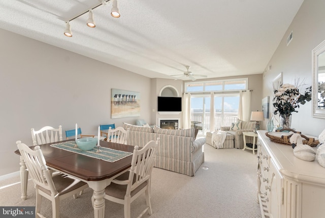 dining space with a textured ceiling, ceiling fan, and light colored carpet