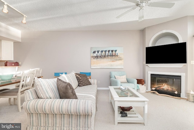 living room featuring carpet floors, ceiling fan, a textured ceiling, and rail lighting