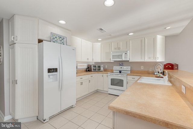 kitchen with light tile patterned flooring, white cabinetry, sink, and white appliances