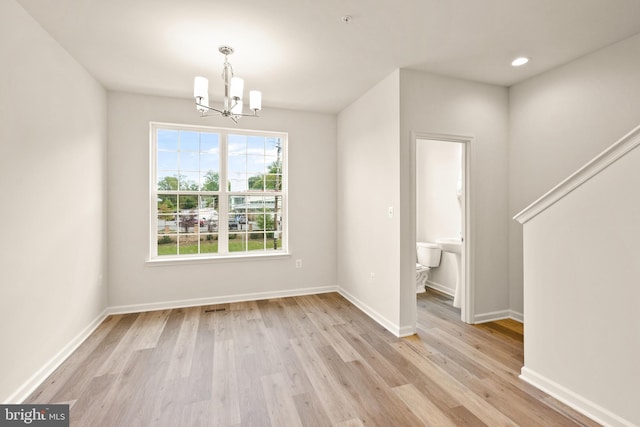 unfurnished dining area featuring a notable chandelier and light hardwood / wood-style floors