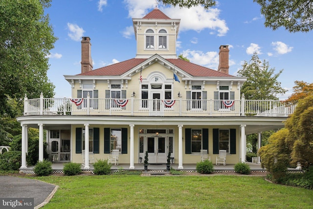 view of front of home with french doors, a balcony, a porch, and a front yard