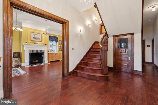 stairway featuring hardwood / wood-style flooring, a fireplace, and a notable chandelier