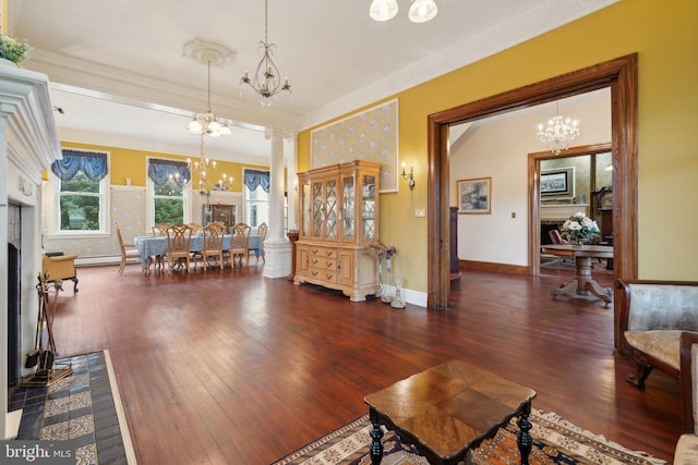 living room with decorative columns, dark wood-type flooring, and a baseboard heating unit