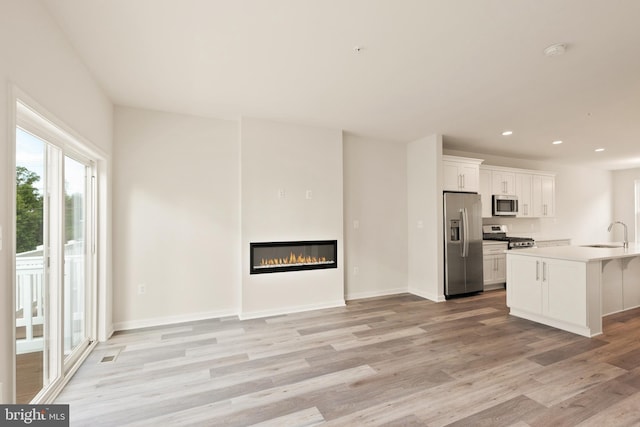 unfurnished living room featuring sink and light wood-type flooring