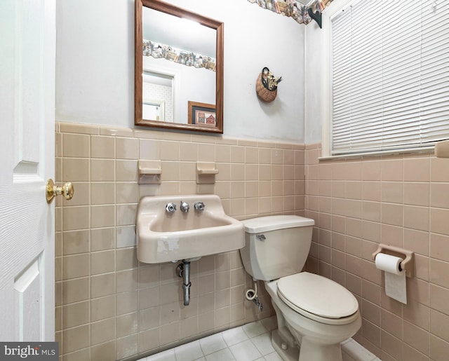 bathroom with tile patterned flooring, sink, toilet, and tile walls