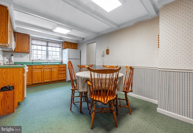 carpeted dining space with beamed ceiling and sink