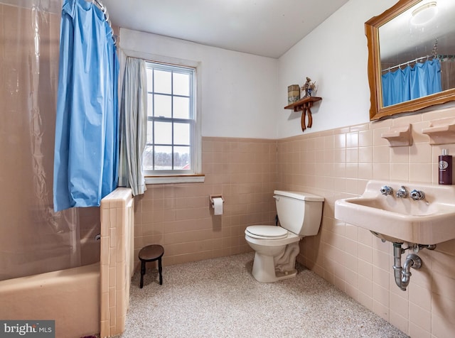 full bathroom featuring shower / bath combination with curtain, toilet, tile walls, and sink