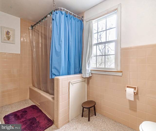 bathroom with plenty of natural light, toilet, shower / bath combo, and tile walls