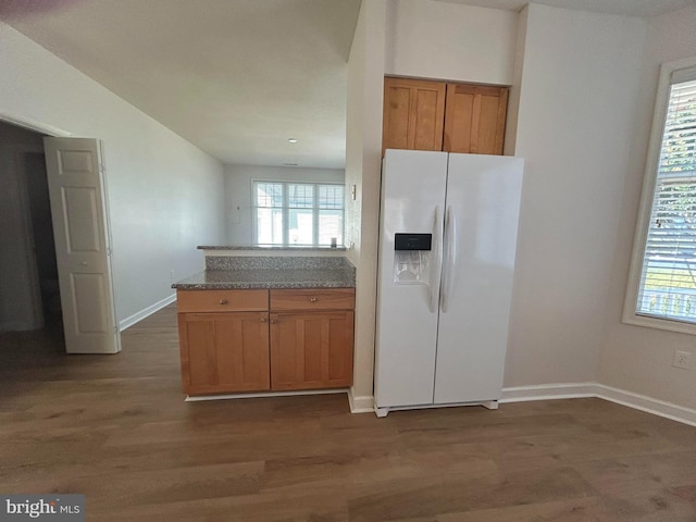 kitchen featuring white fridge with ice dispenser, dark wood-type flooring, and stone countertops