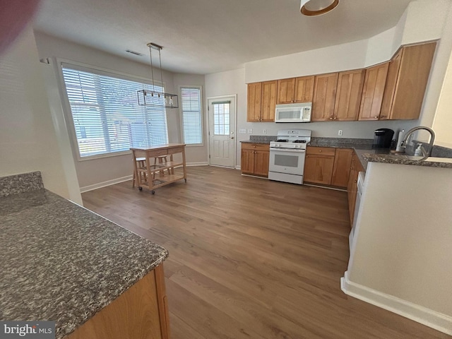 kitchen featuring pendant lighting, white appliances, dark hardwood / wood-style flooring, and sink