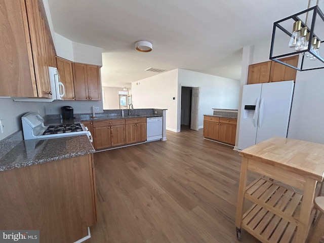 kitchen with kitchen peninsula, white appliances, dark wood-type flooring, sink, and pendant lighting