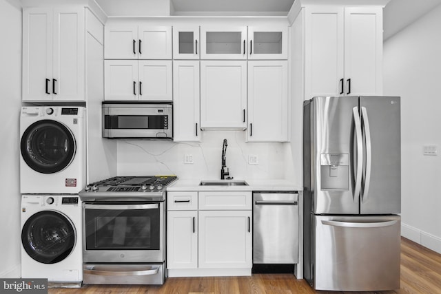 kitchen featuring stacked washer / dryer, white cabinetry, sink, and stainless steel appliances