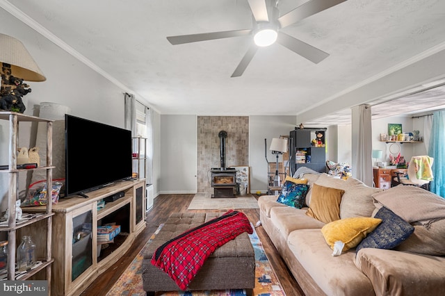 living room with ceiling fan, a wood stove, and ornamental molding