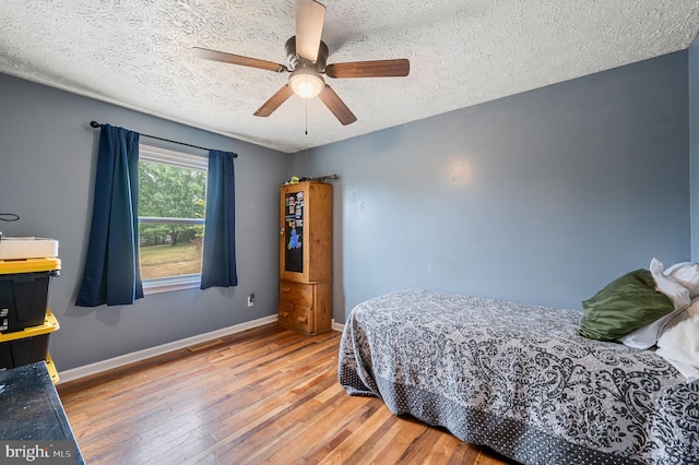 bedroom with ceiling fan, a textured ceiling, and hardwood / wood-style floors