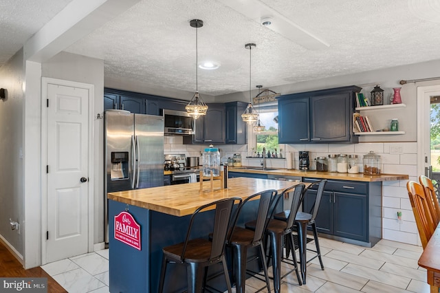 kitchen featuring tasteful backsplash, a breakfast bar, blue cabinets, and wood counters