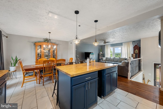 kitchen with a kitchen island, pendant lighting, butcher block countertops, a breakfast bar area, and blue cabinets