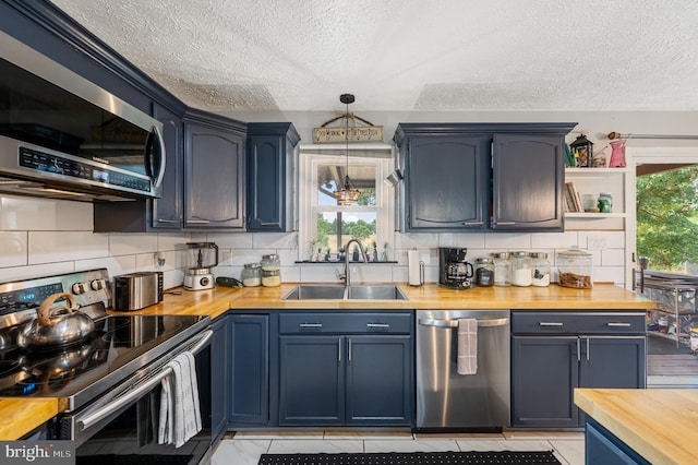 kitchen featuring sink, pendant lighting, appliances with stainless steel finishes, and butcher block counters