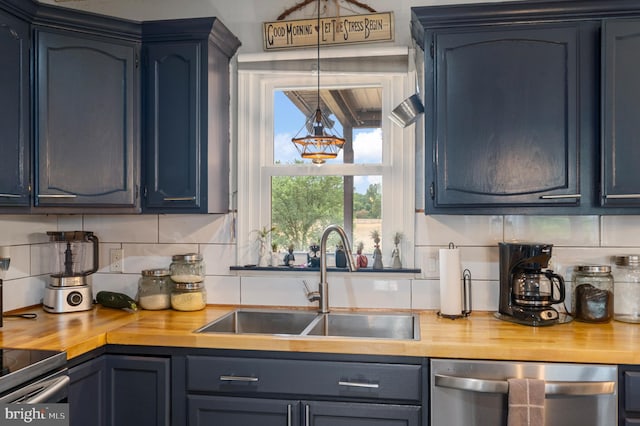 kitchen with butcher block countertops, backsplash, blue cabinets, stainless steel dishwasher, and sink