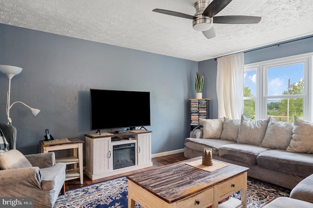 living room with a textured ceiling, ceiling fan, and hardwood / wood-style flooring