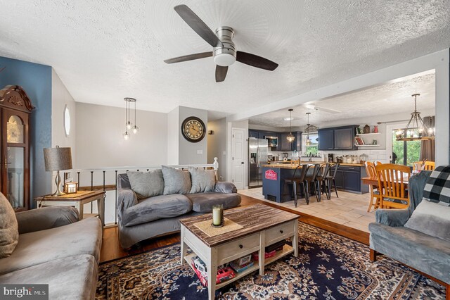 living room with ceiling fan with notable chandelier, a textured ceiling, and hardwood / wood-style floors