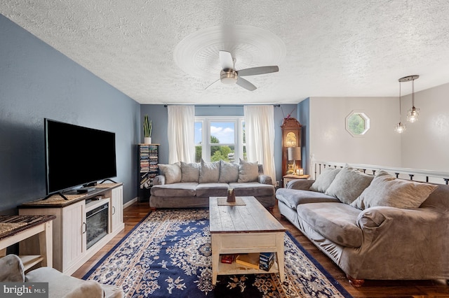 living room featuring a textured ceiling, dark wood-type flooring, and ceiling fan