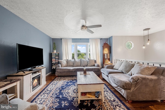 living room featuring a textured ceiling, ceiling fan, and dark hardwood / wood-style flooring