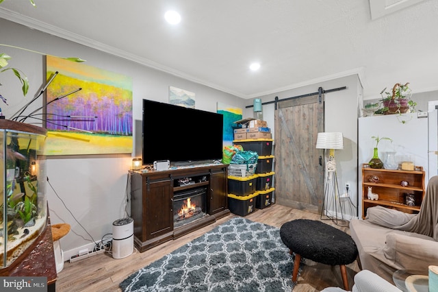 living room with crown molding, a barn door, and light hardwood / wood-style flooring