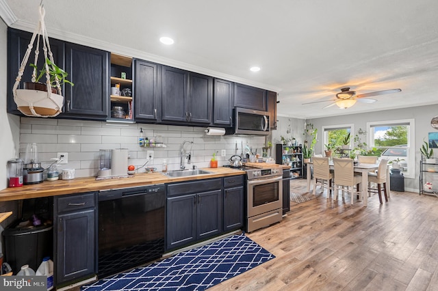 kitchen featuring wooden counters, decorative backsplash, appliances with stainless steel finishes, and sink