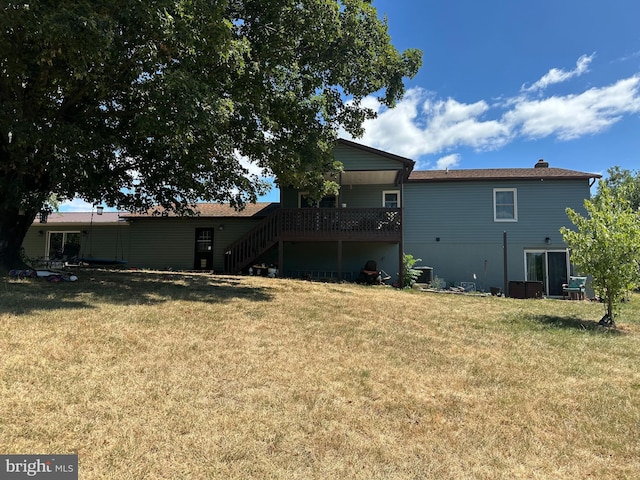 rear view of property with a wooden deck and a lawn