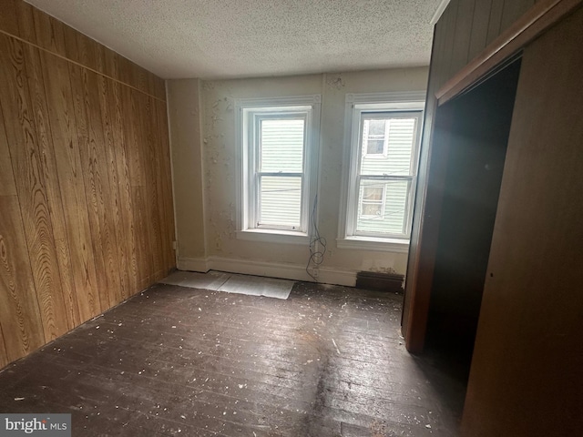 empty room with a textured ceiling and wooden walls