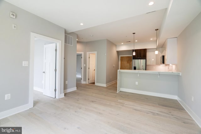 kitchen with a kitchen bar, kitchen peninsula, white cabinetry, stainless steel appliances, and dark brown cabinets